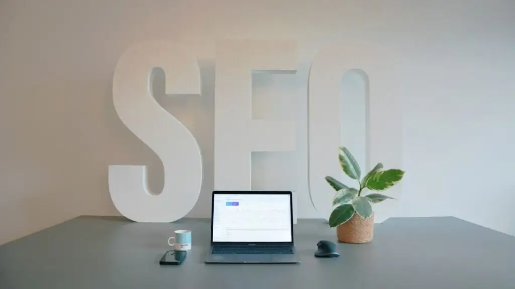 Mesa com notebook e ao fundo escrito SEO